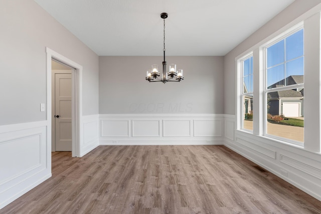 unfurnished dining area with a chandelier and light hardwood / wood-style flooring