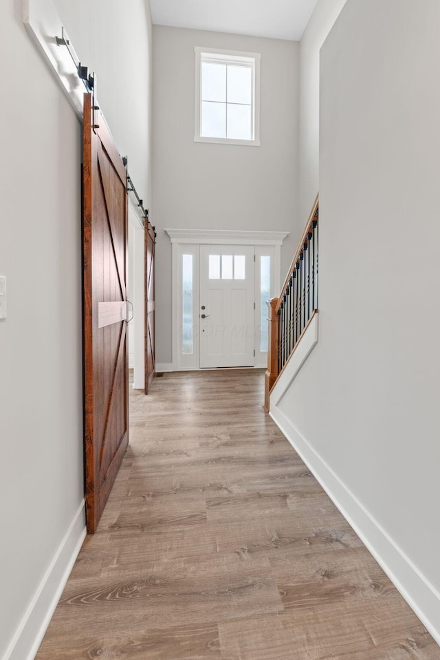 foyer entrance with light wood-type flooring and a barn door