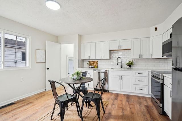 kitchen featuring hardwood / wood-style floors, appliances with stainless steel finishes, white cabinetry, and sink