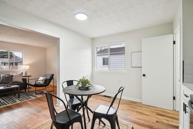 dining room featuring a textured ceiling and light hardwood / wood-style flooring