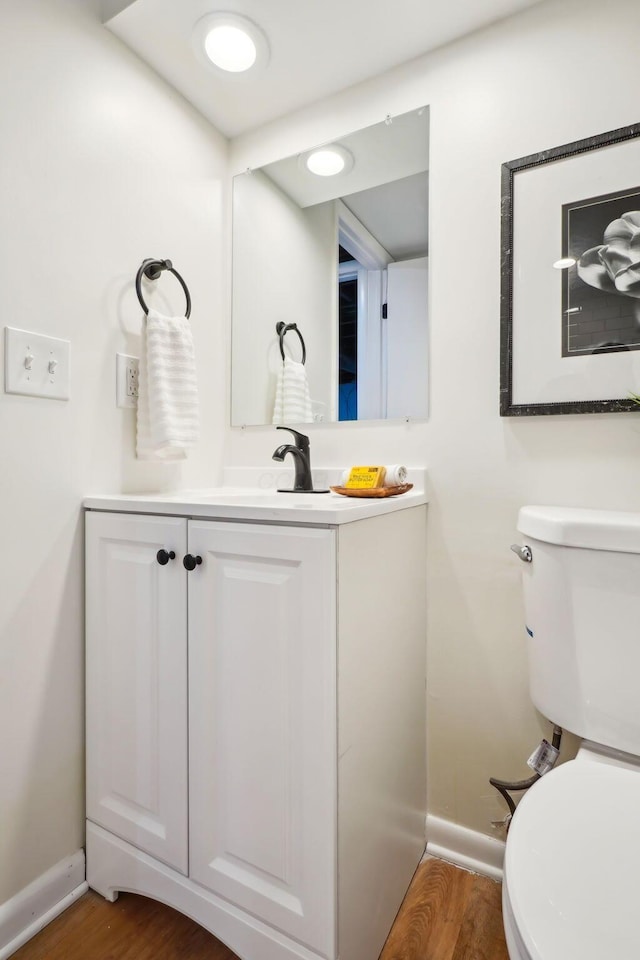 bathroom with hardwood / wood-style flooring, vanity, and toilet