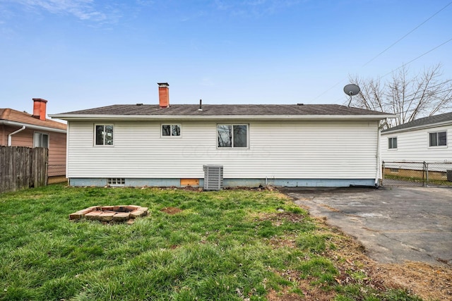 back of property featuring central AC, a yard, and a fire pit