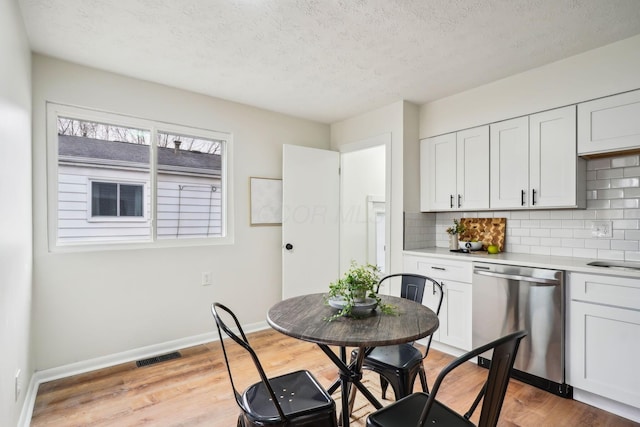 dining area with a textured ceiling and light hardwood / wood-style floors