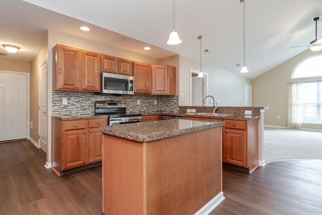 kitchen featuring appliances with stainless steel finishes, pendant lighting, sink, a center island, and kitchen peninsula