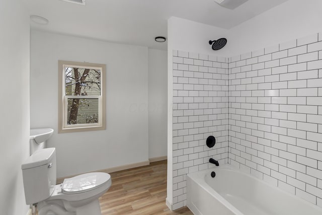 bathroom featuring toilet, wood-type flooring, and tiled shower / bath