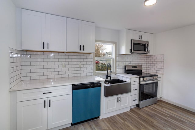 kitchen with backsplash, sink, light hardwood / wood-style floors, white cabinetry, and stainless steel appliances