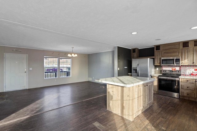 kitchen featuring dark hardwood / wood-style flooring, tasteful backsplash, stainless steel appliances, an inviting chandelier, and a center island