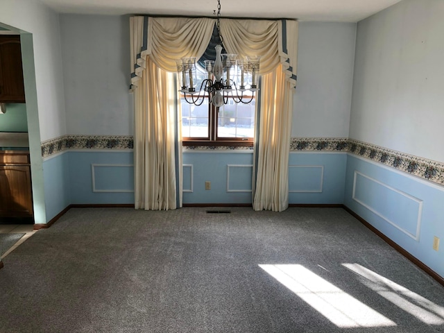 unfurnished dining area featuring carpet flooring and a notable chandelier