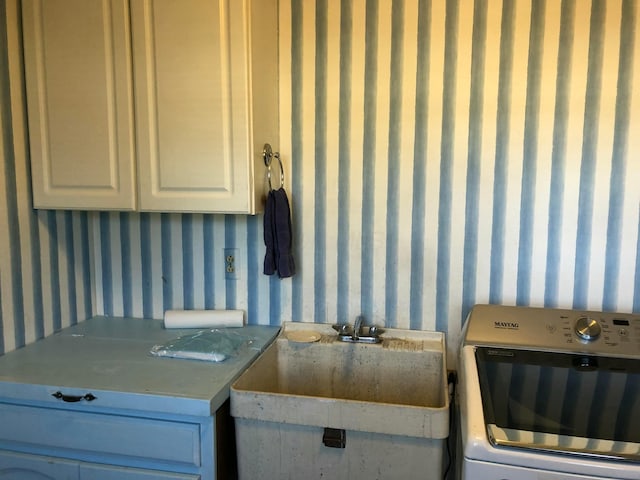 clothes washing area featuring cabinets, washer / dryer, and sink