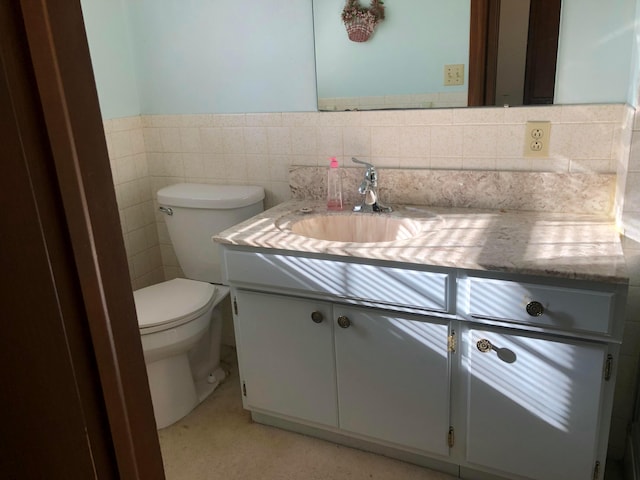 bathroom featuring vanity, tile walls, and toilet