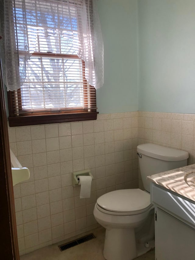 bathroom featuring tile patterned floors, vanity, toilet, and tile walls