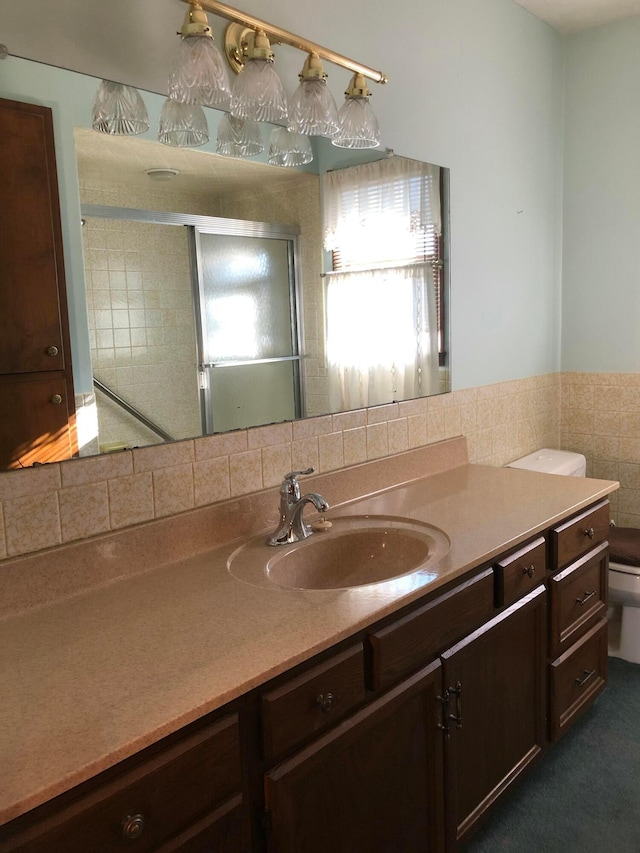 bathroom with a shower with door, vanity, and toilet