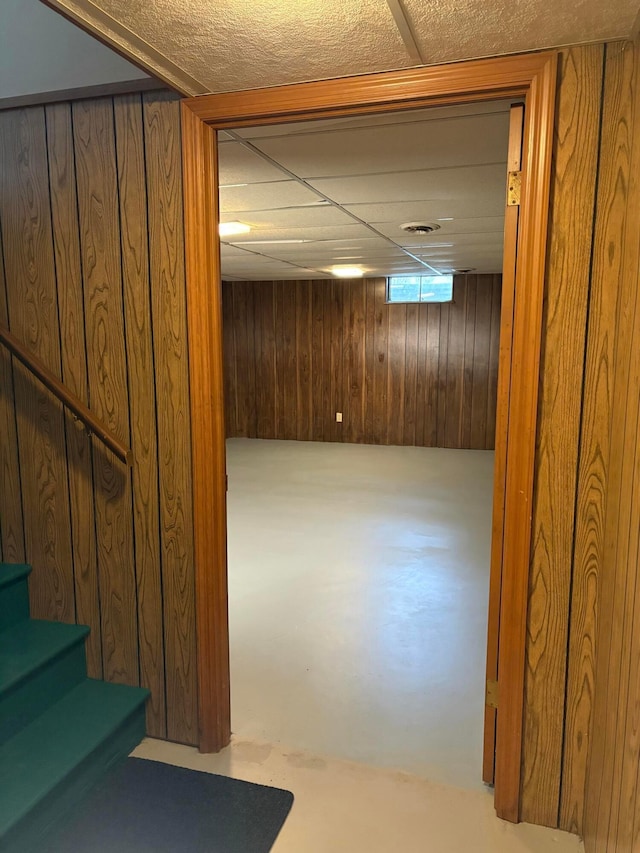 basement with a paneled ceiling and wooden walls