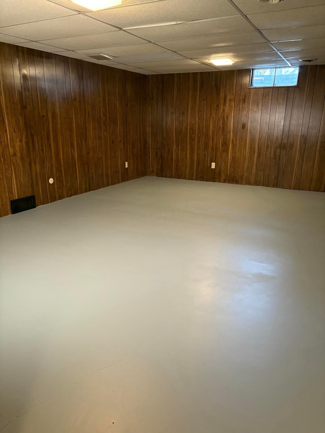 basement with wood walls and a drop ceiling