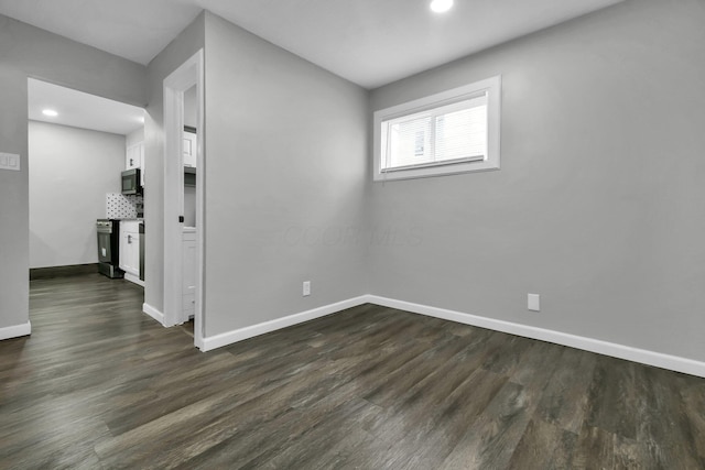 spare room with dark wood-type flooring, recessed lighting, and baseboards