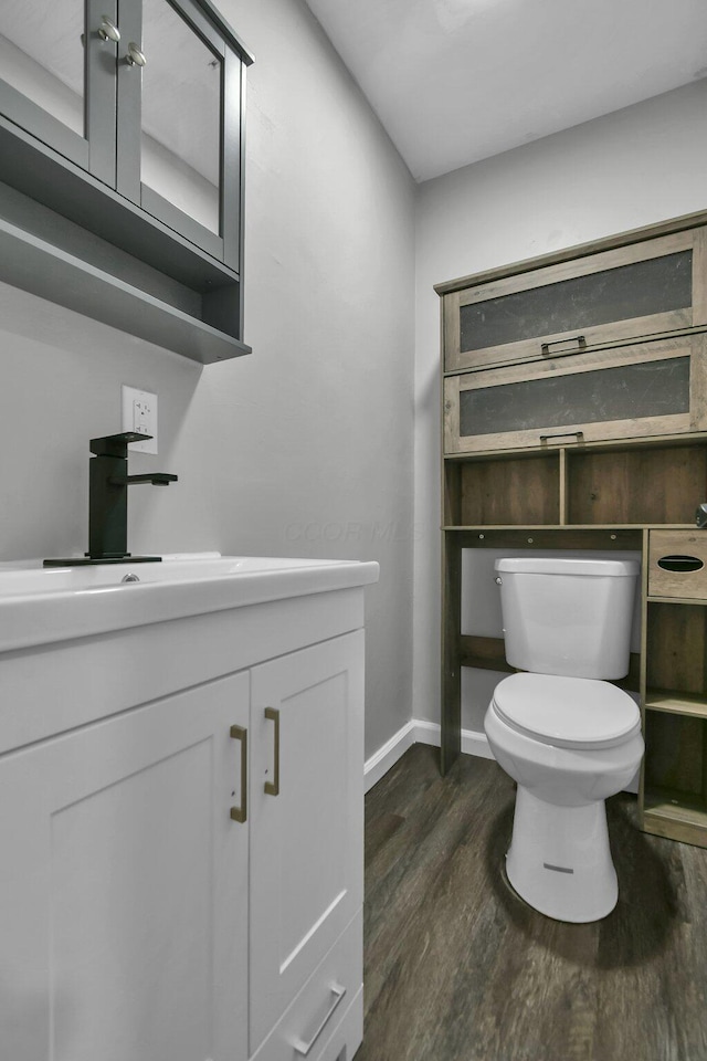 bathroom featuring baseboards, vanity, toilet, and wood finished floors