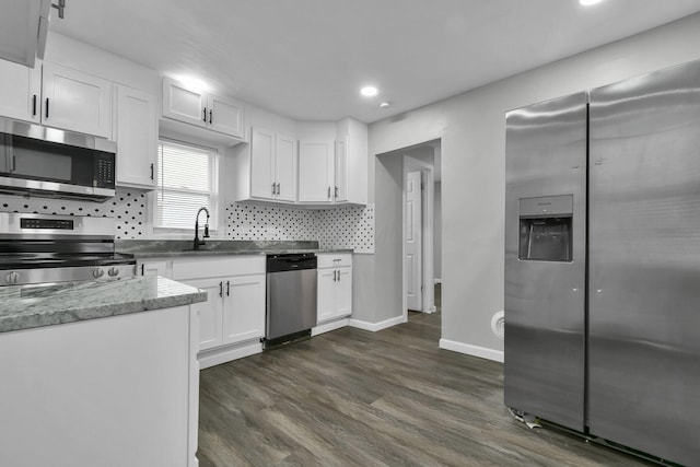 kitchen featuring stainless steel appliances, dark wood-style flooring, a sink, white cabinets, and backsplash