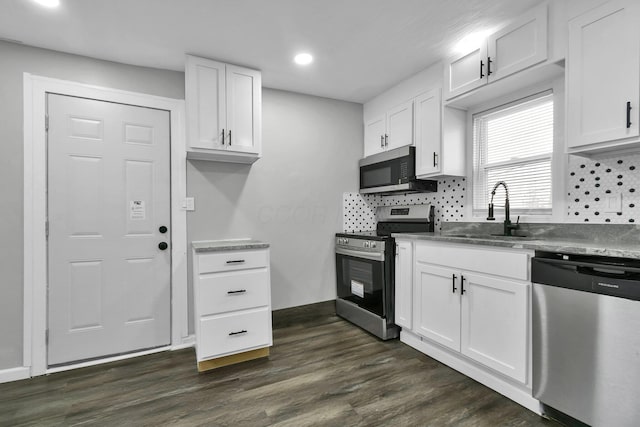 kitchen featuring dark wood-style flooring, decorative backsplash, appliances with stainless steel finishes, white cabinetry, and a sink