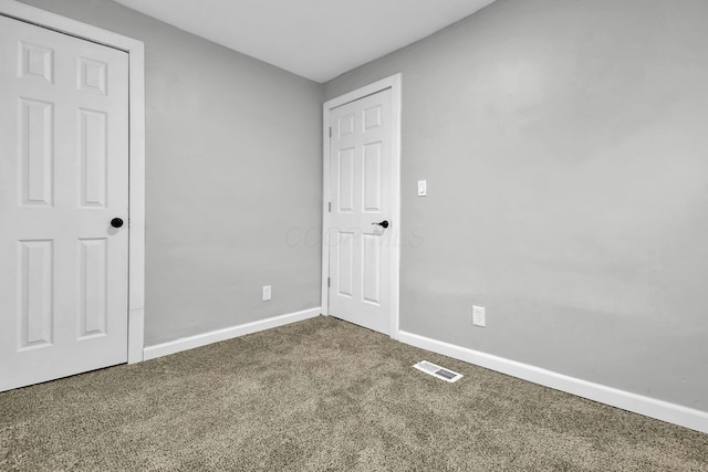 unfurnished bedroom with carpet floors, baseboards, and visible vents