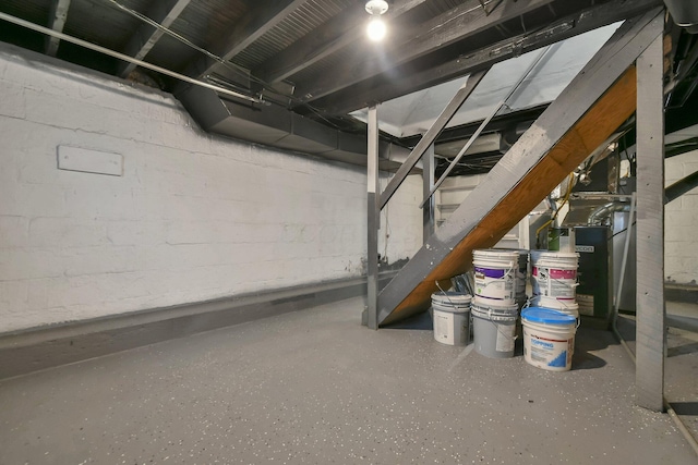 unfinished basement with concrete block wall and stairway