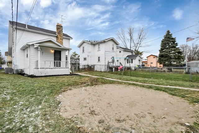 rear view of house with a chimney, fence, and a yard