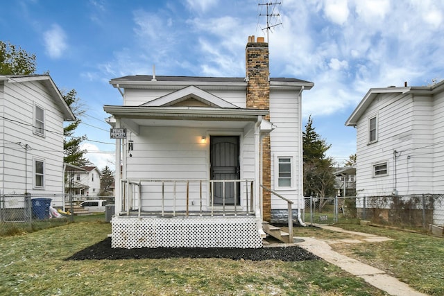 rear view of house with a yard, fence, and a chimney