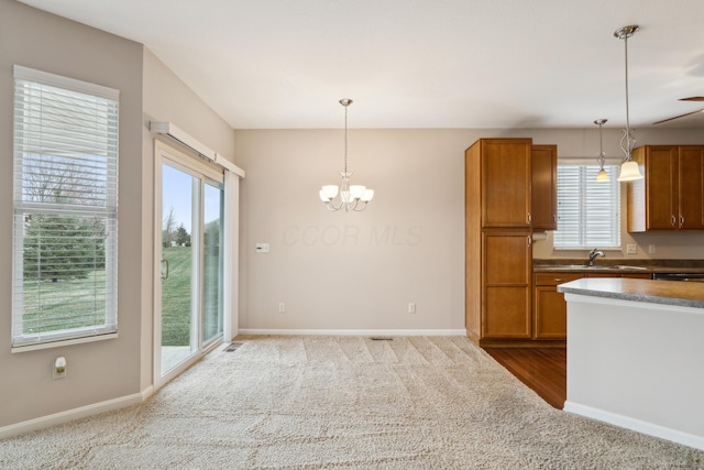 kitchen with decorative light fixtures, light colored carpet, and sink