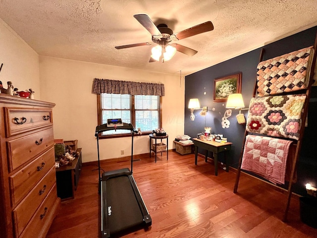 exercise room featuring hardwood / wood-style floors, a textured ceiling, and ceiling fan