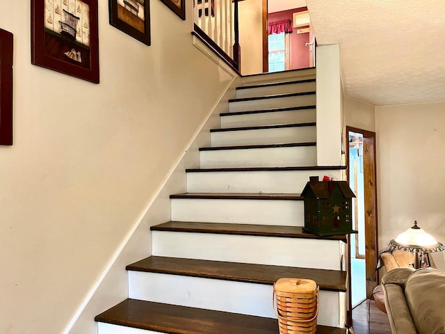 staircase featuring hardwood / wood-style flooring and a textured ceiling