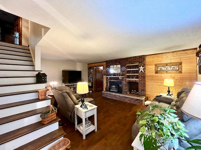 living room with a textured ceiling, wooden walls, a fireplace, and dark hardwood / wood-style floors