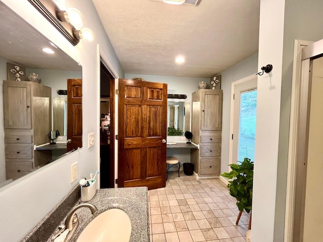 bathroom with a textured ceiling, vanity, and tile patterned floors