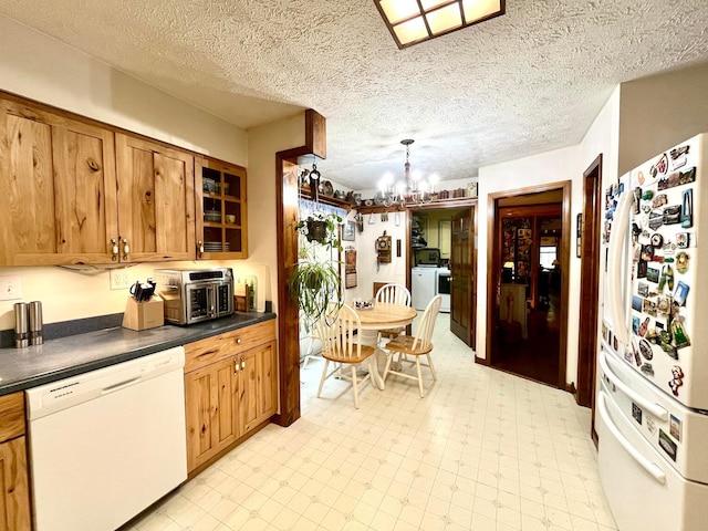 kitchen with white appliances, a textured ceiling, decorative light fixtures, washer / clothes dryer, and a chandelier