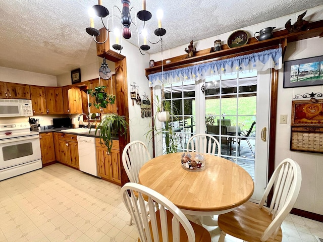 kitchen featuring sink, an inviting chandelier, pendant lighting, a textured ceiling, and white appliances