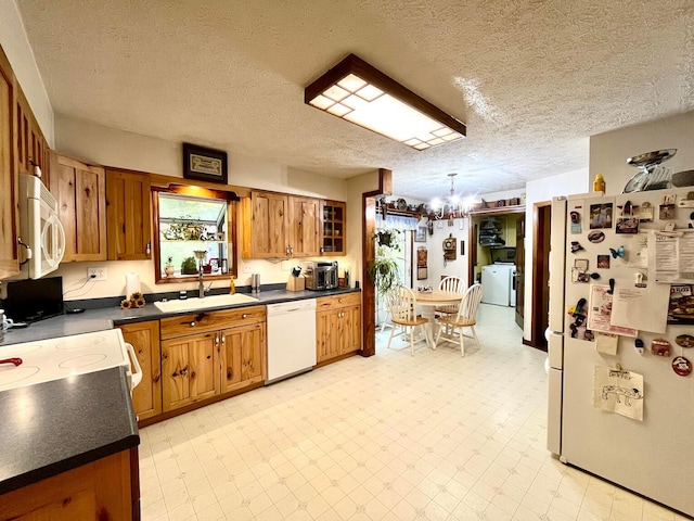 kitchen with sink, hanging light fixtures, an inviting chandelier, a textured ceiling, and white appliances