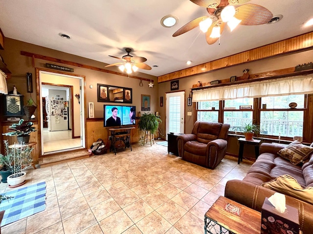 tiled living room with ceiling fan and wooden walls