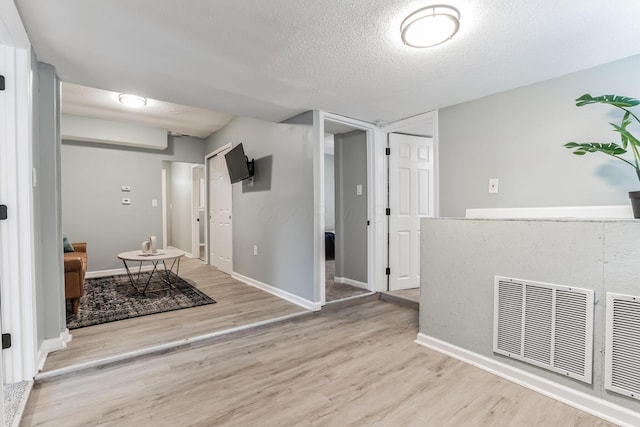 corridor featuring light wood-type flooring and a textured ceiling