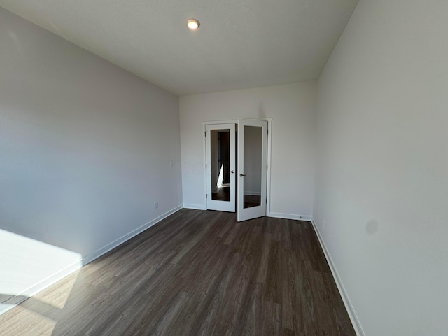 unfurnished room with baseboards and dark wood-style floors