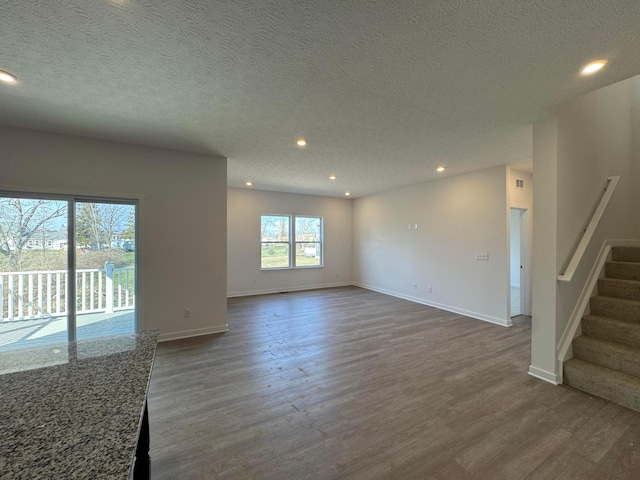 unfurnished living room featuring dark wood-style flooring, stairs, and recessed lighting
