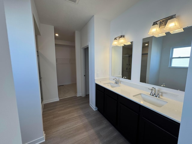 bathroom featuring a stall shower, a walk in closet, wood finished floors, and a sink