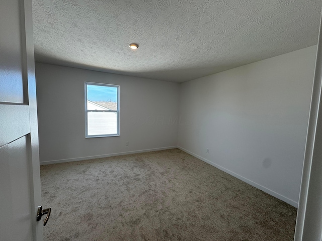empty room featuring carpet floors, baseboards, and a textured ceiling