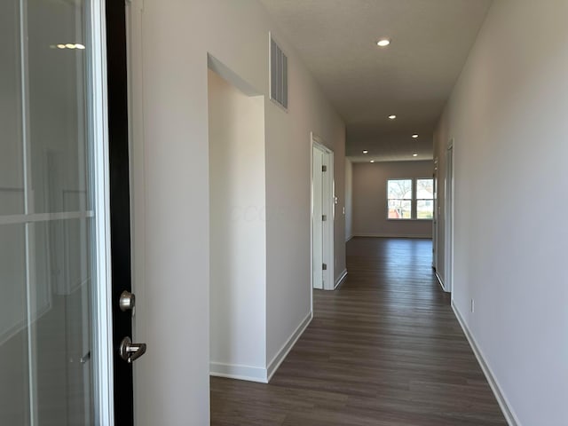 hall with dark wood-style floors, visible vents, baseboards, and recessed lighting