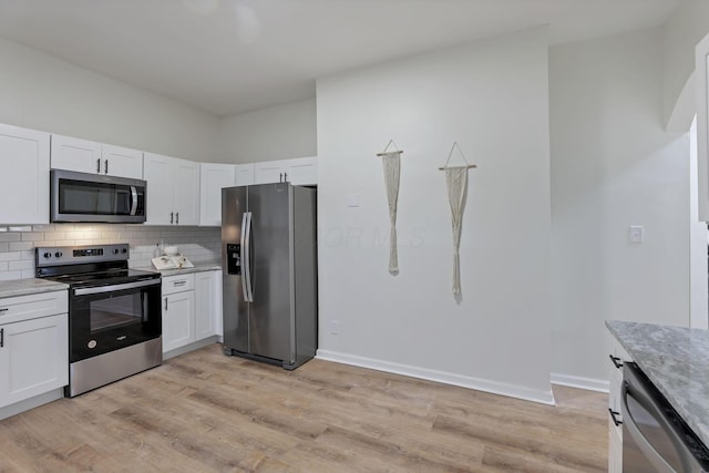 kitchen with white cabinets, light wood-type flooring, light stone countertops, tasteful backsplash, and stainless steel appliances