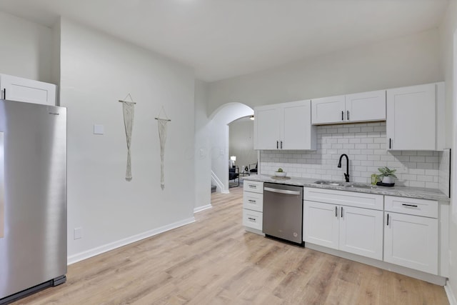 kitchen featuring white cabinetry, sink, light stone countertops, and appliances with stainless steel finishes