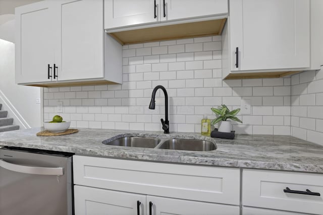 kitchen featuring light stone countertops, backsplash, white cabinets, sink, and dishwasher