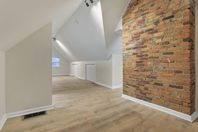 additional living space with vaulted ceiling and light wood-type flooring