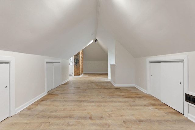 additional living space featuring light hardwood / wood-style floors and lofted ceiling