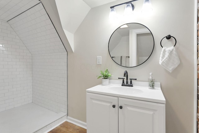 bathroom featuring vanity, lofted ceiling, and tiled shower