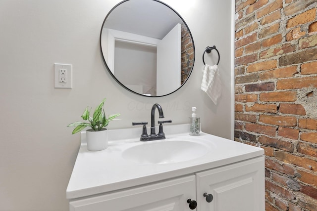 bathroom featuring vanity and brick wall