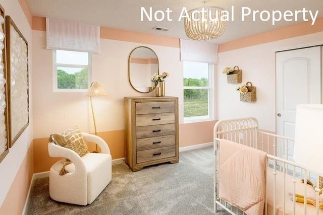 carpeted bedroom featuring a crib and a notable chandelier