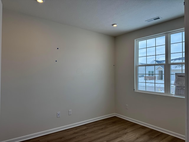 empty room with dark hardwood / wood-style flooring, a wealth of natural light, and a textured ceiling